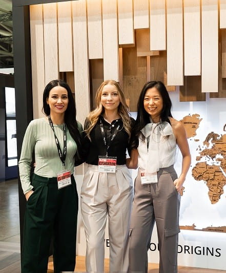 Interior Design students Gigi Dybalski, Natalie Guberney and Jenny Huggon stand side-by-side in front of an installation they designed for Metropolitan Floors' booth at the 2024 Interior Design Show Toronto.