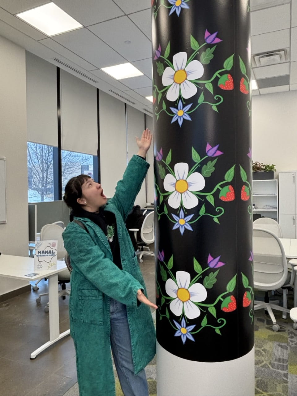 Kanerahtaien Doxtador-Swamp proudly points to her artwork that is wrapped around a pillar at Sheridan's Hazel McCallion Campus