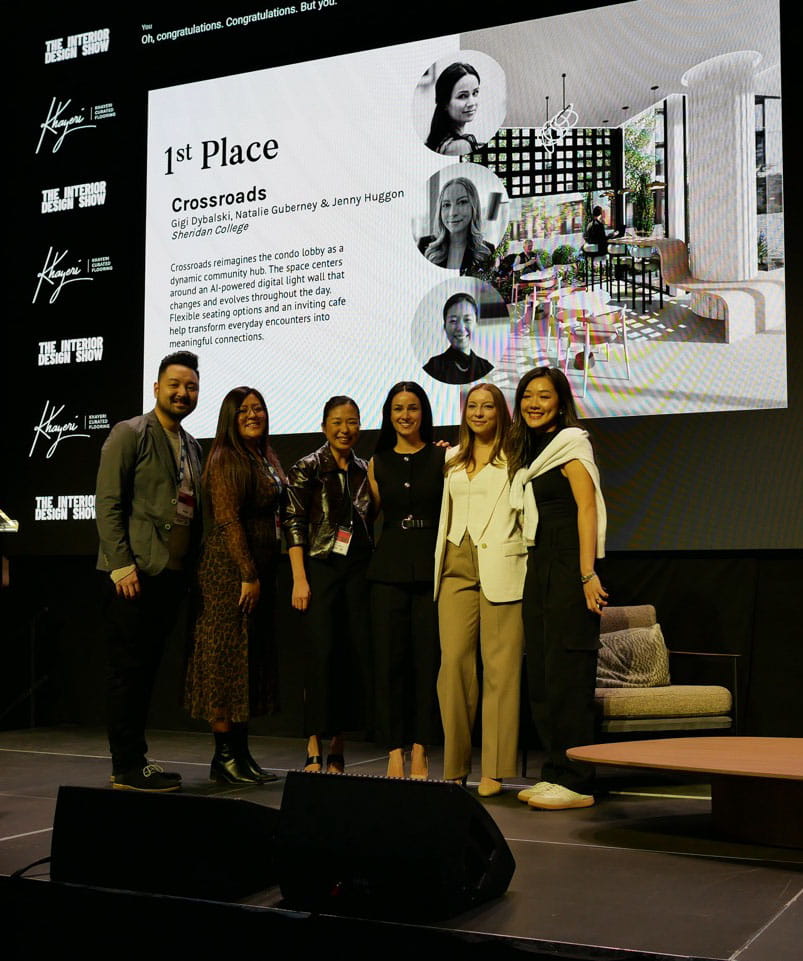 Sheridan Interior Design students Natalie Guberney, Gigi Dybalski and Jenny Huggon stand on the stage of the Interior Design Show Toronto, with their winning project displayed in the background. 