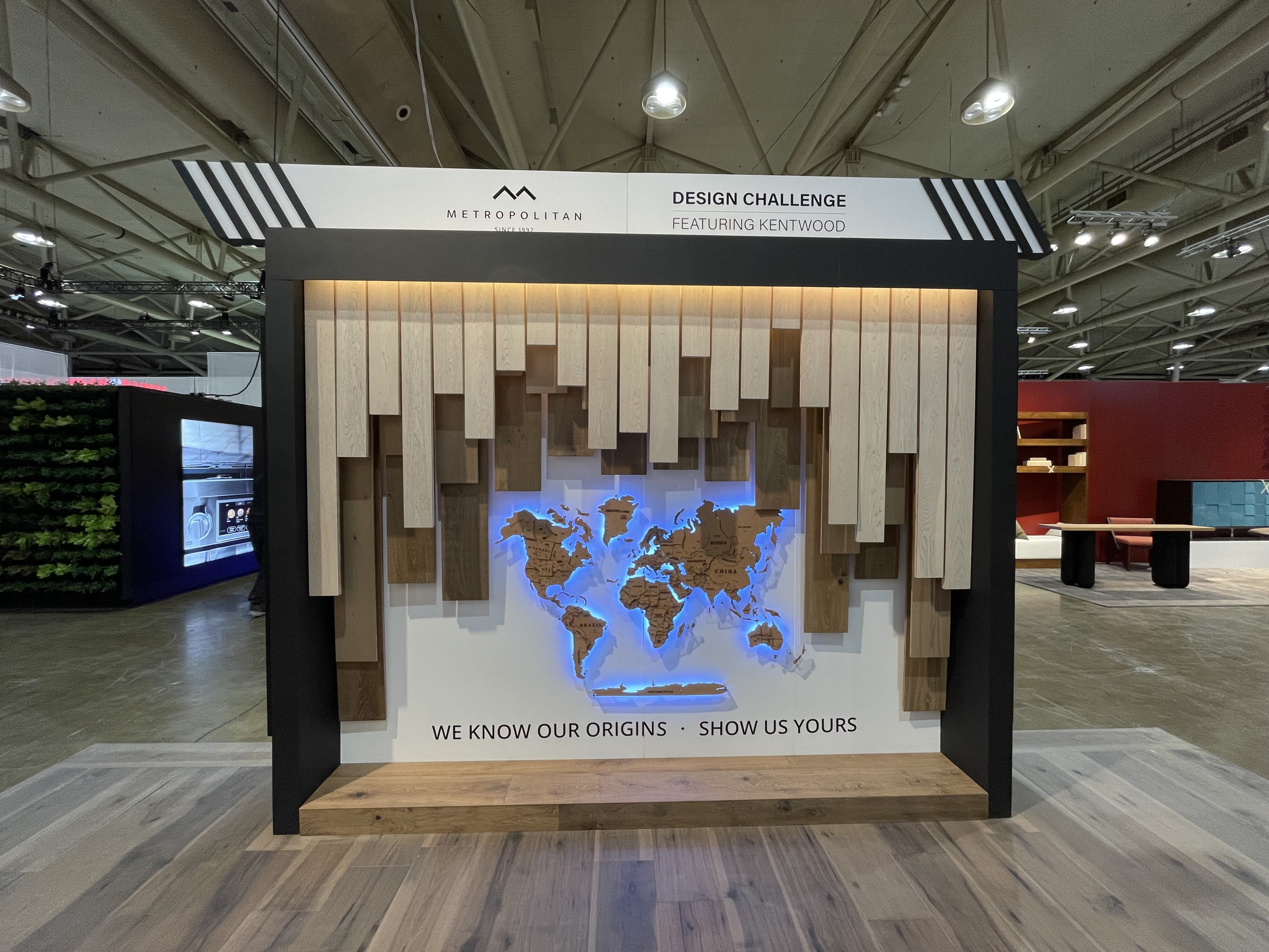 An installation titled 'Origins' that uses three distinct flooring products to create layers of depth around a world map, inviting users to share their origins by placing a pin on the map.