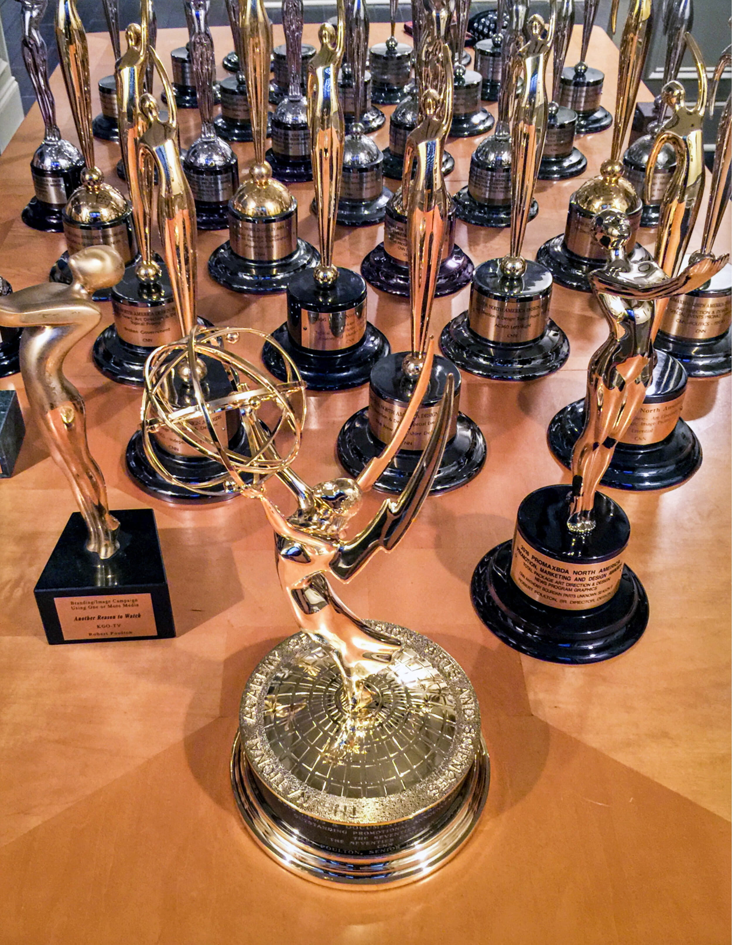 An image displaying Robert Poulton's many awards, including an Emmy.