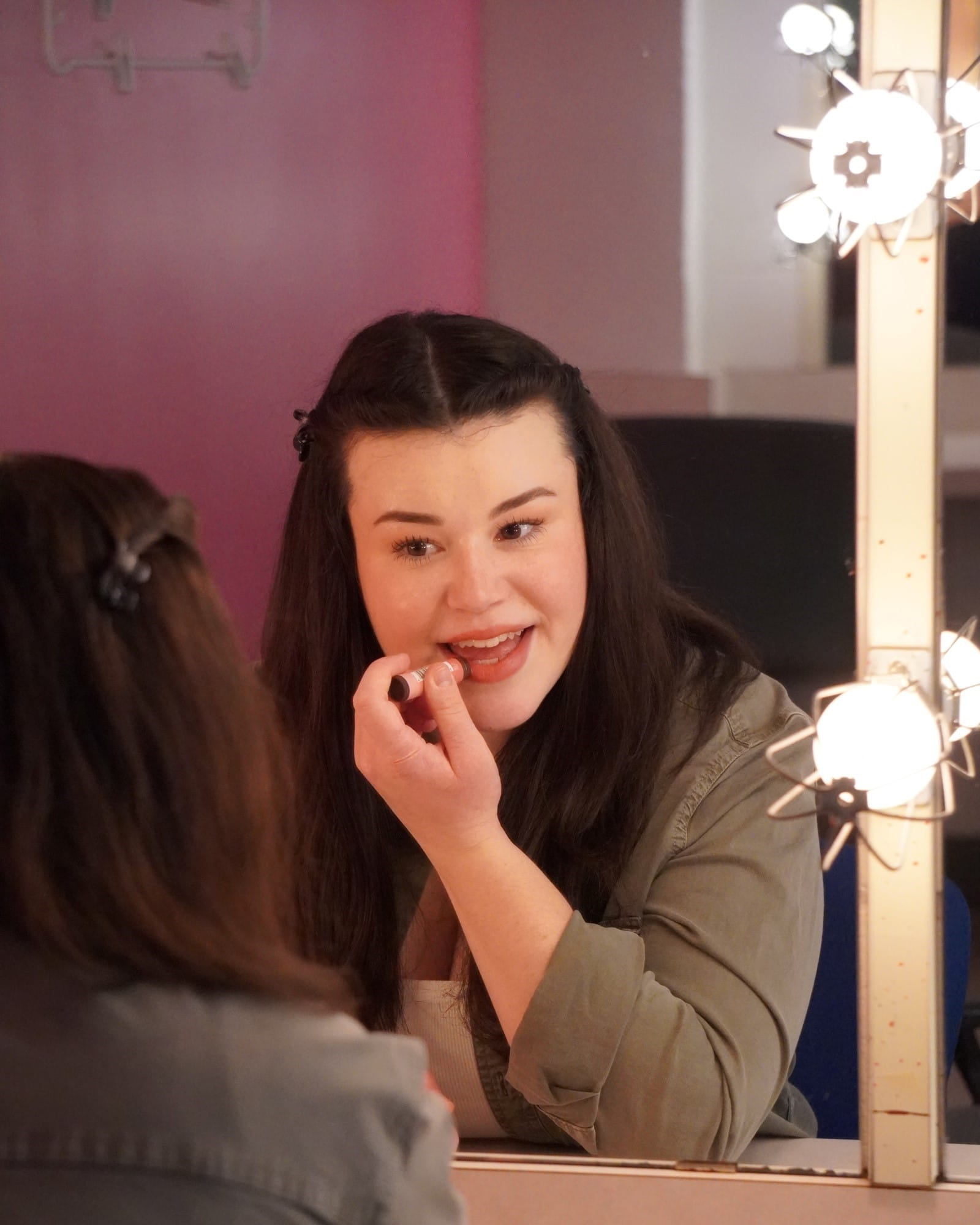 Sydney Brown looks in the mirror while applying lipstick.