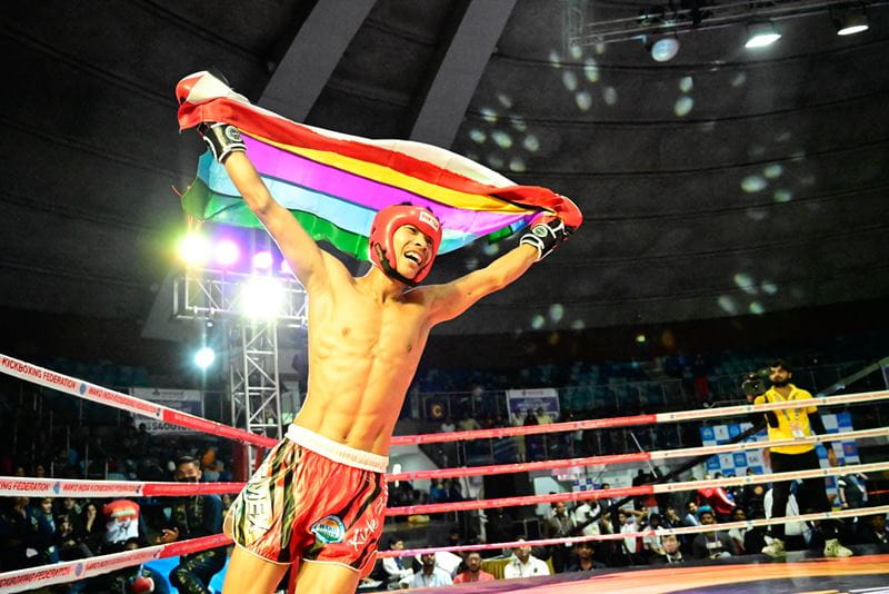 An award-winning photo of a kickboxer holding up a flag in the ring as he celebrates a victory