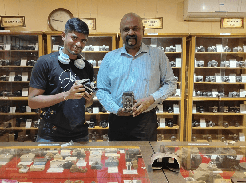 Sheridan photography student Tanishq Arun and his father stand inside their museum of film cameras, located in India