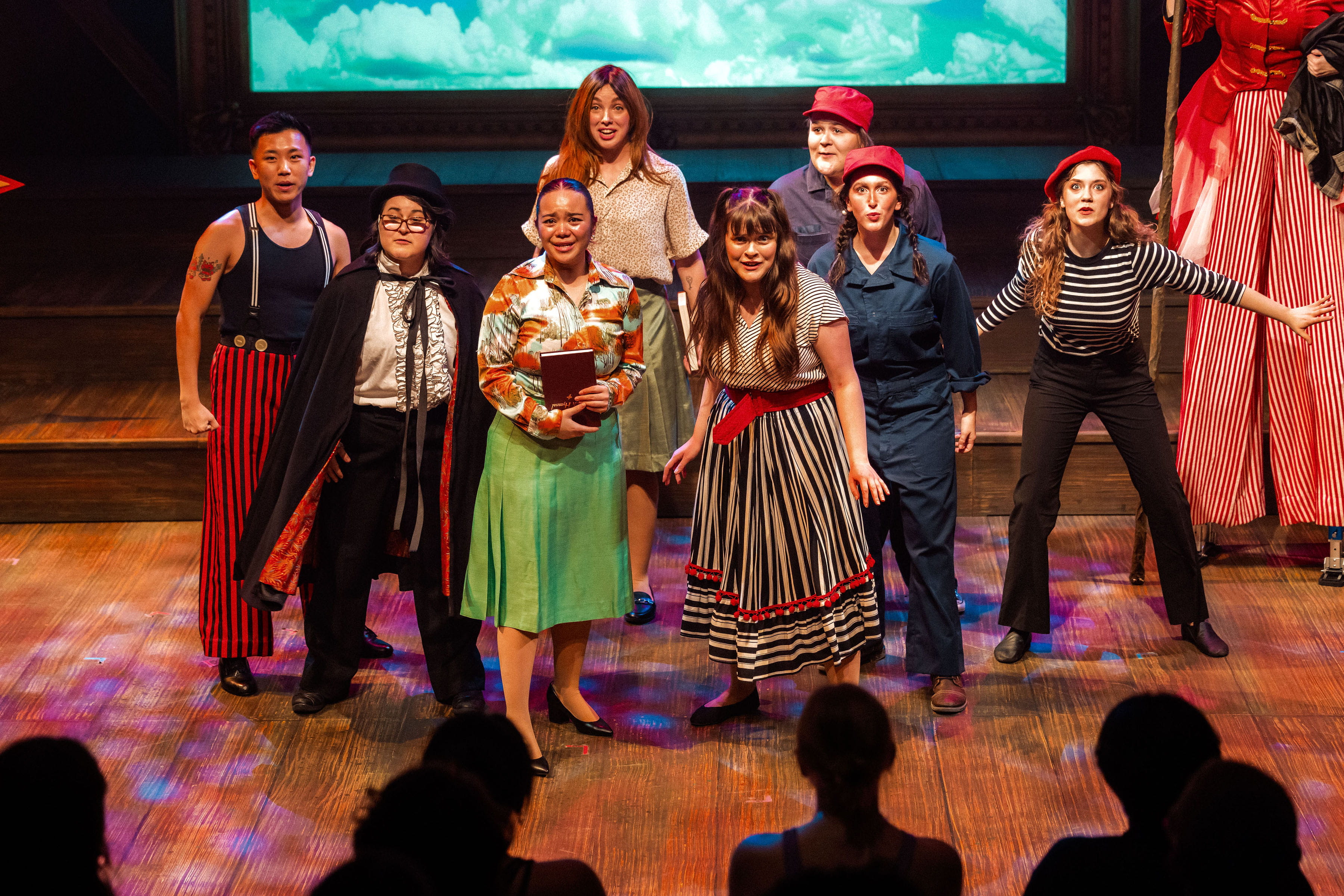 Eight actors in costume from the production of Big Fish pose together on stage.
