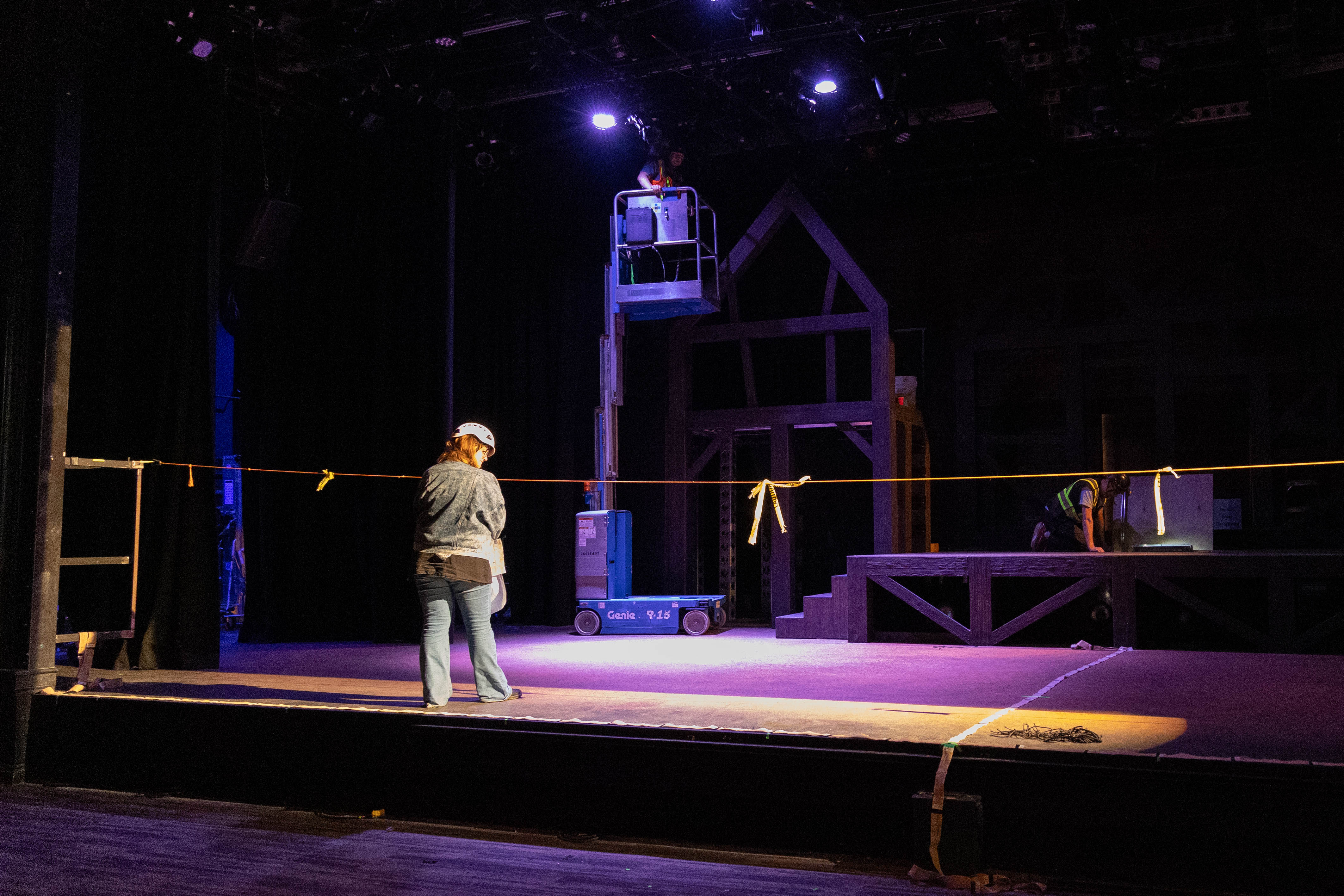 A lighting crew member stands on stage to work on the lighting element of a production.
