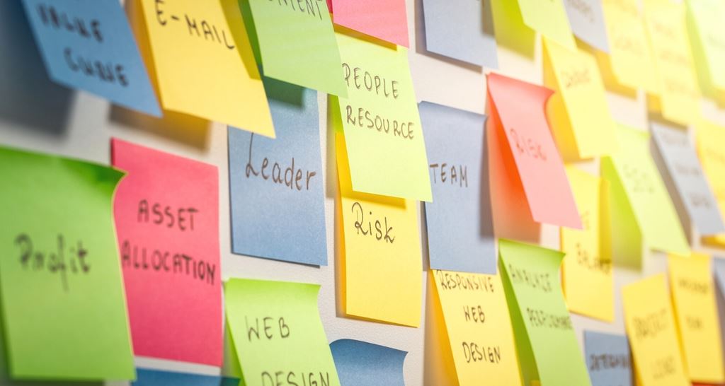 A collection of colourful sticky notes with writing on a wall.