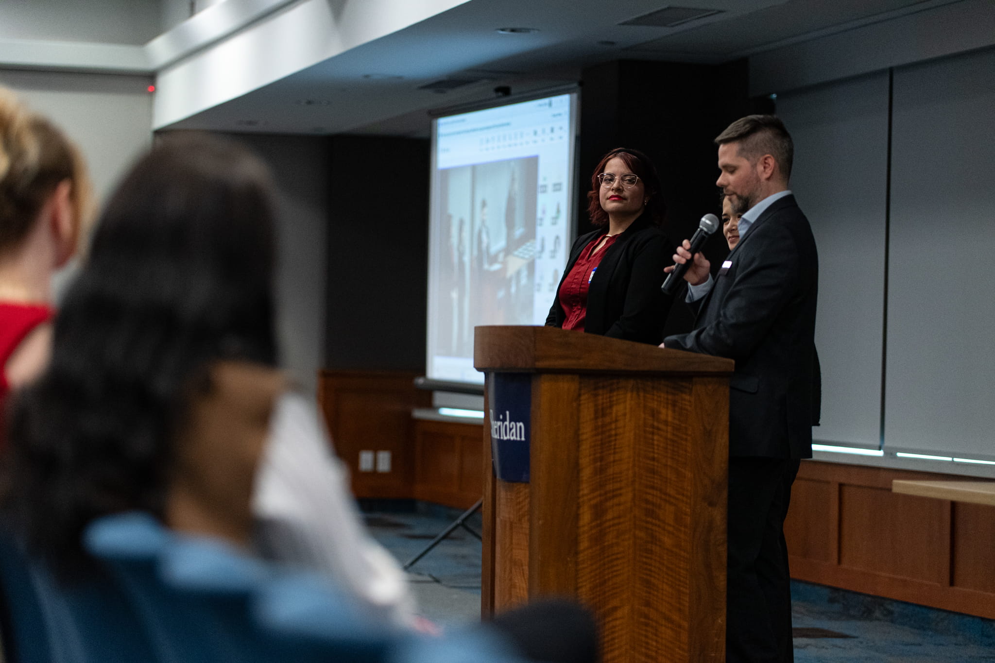 Sheridan's Associate Director, Cooperative and Career Education, Cory Latimer stands at a podium to present a work-integrated learning award to a student