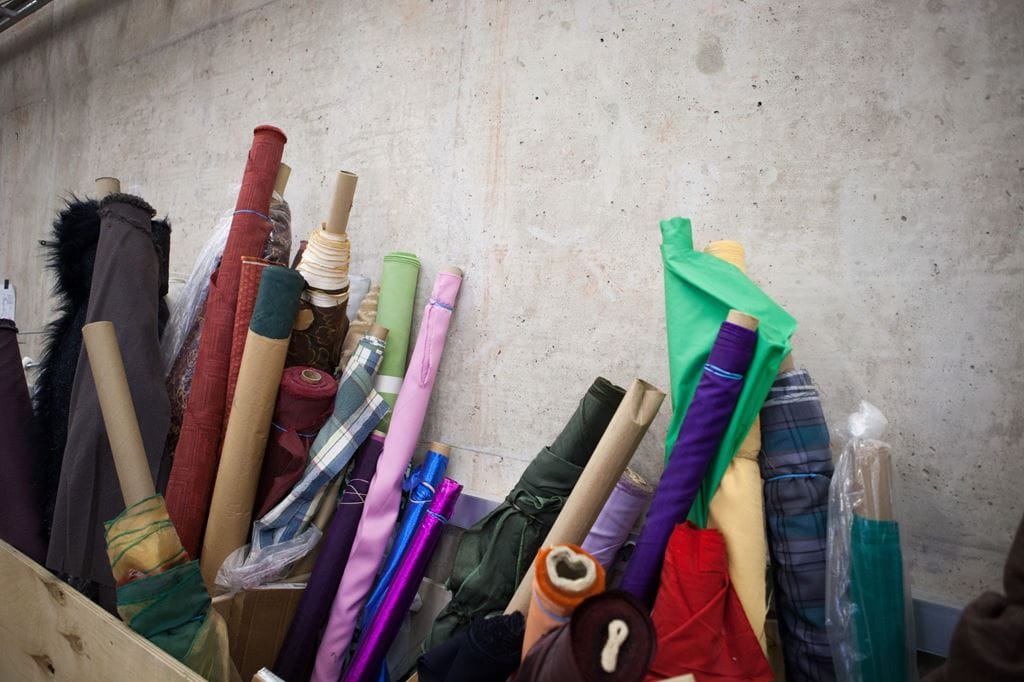 Colourful rolls of fabric leaning against a concrete wall