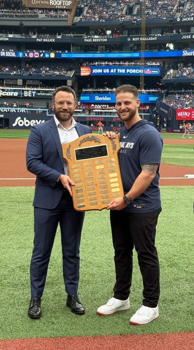Sheridan Athletic Therapy student David Loiacono receives the Sports Medicine Scholarship Award plaque from Dr. David Lawrence during a pre-game presentation on the field of the Rogers Centre.