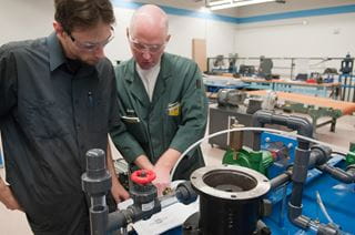 Sheridan Industrial Mechanic Millwright coordinator Craig Brazil works with a student on a machine
