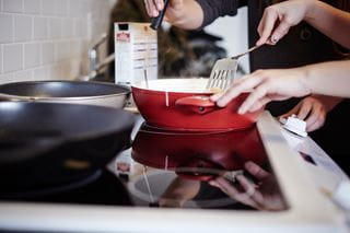Person cooking on a stove with a frying pan and spatula