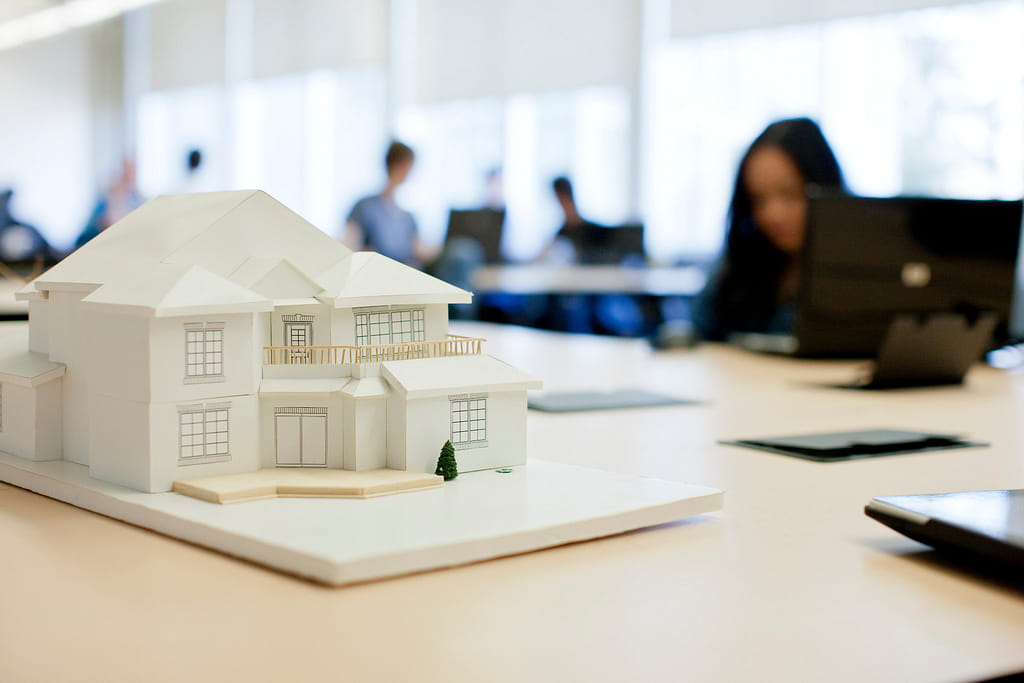 A model home sits on top of a desk in a classroom