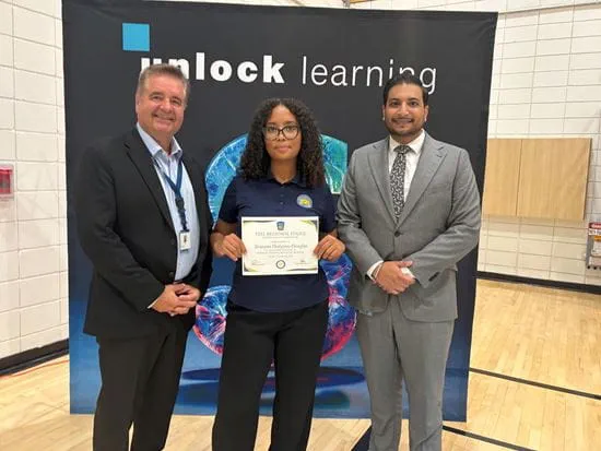Harris Huska, Brianna Hodgson-Douglas and Rajan Sandhu stand in front of a banner that reads unlock learning.
