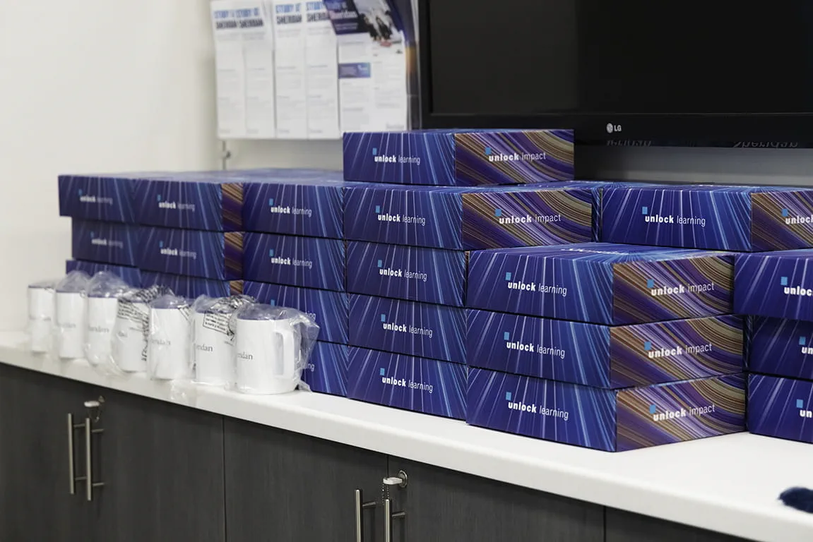 A large stack of Sheridan welcome gifts displayed on a counter in the Admissions Hub