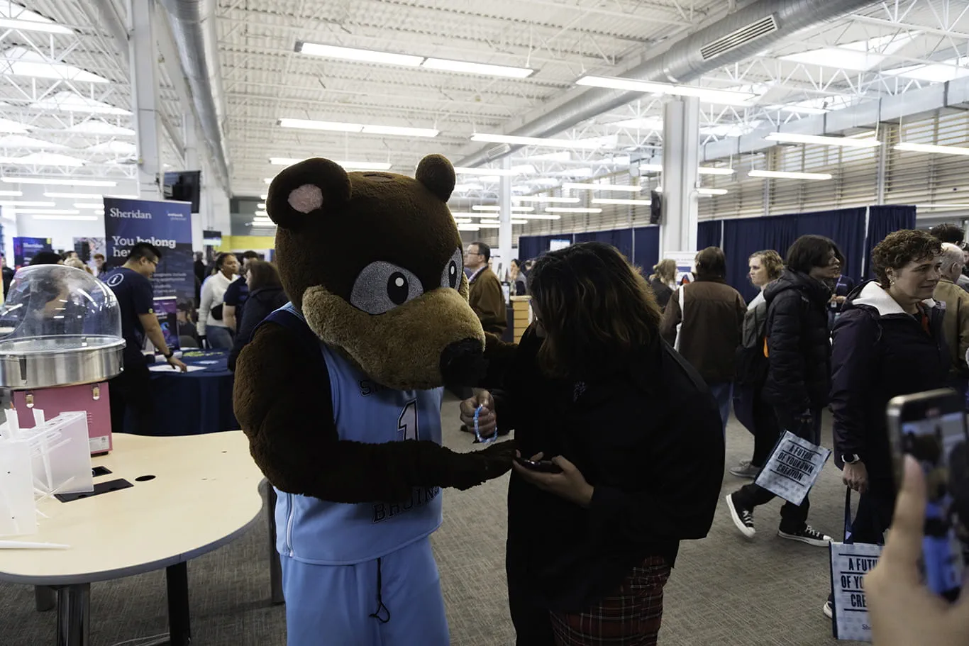 Sheridan's mascot Bruno gifts a friendship bracelet to a Fall Open House attendee