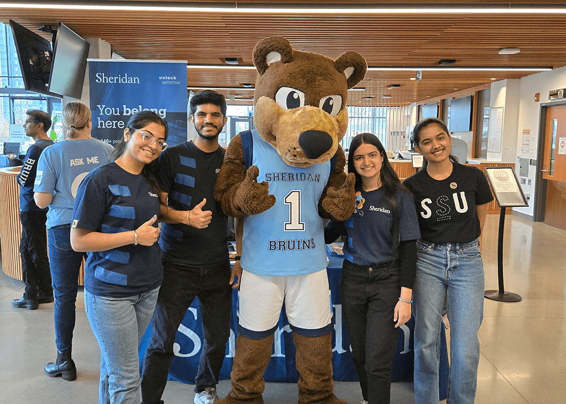 A group of student ambassadors pose for a photo with Sheridan's mascot Bruno