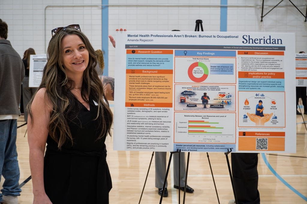 Student Amanda Ragazzon smiles as she sands next to a large printout that displays her capstone research findings