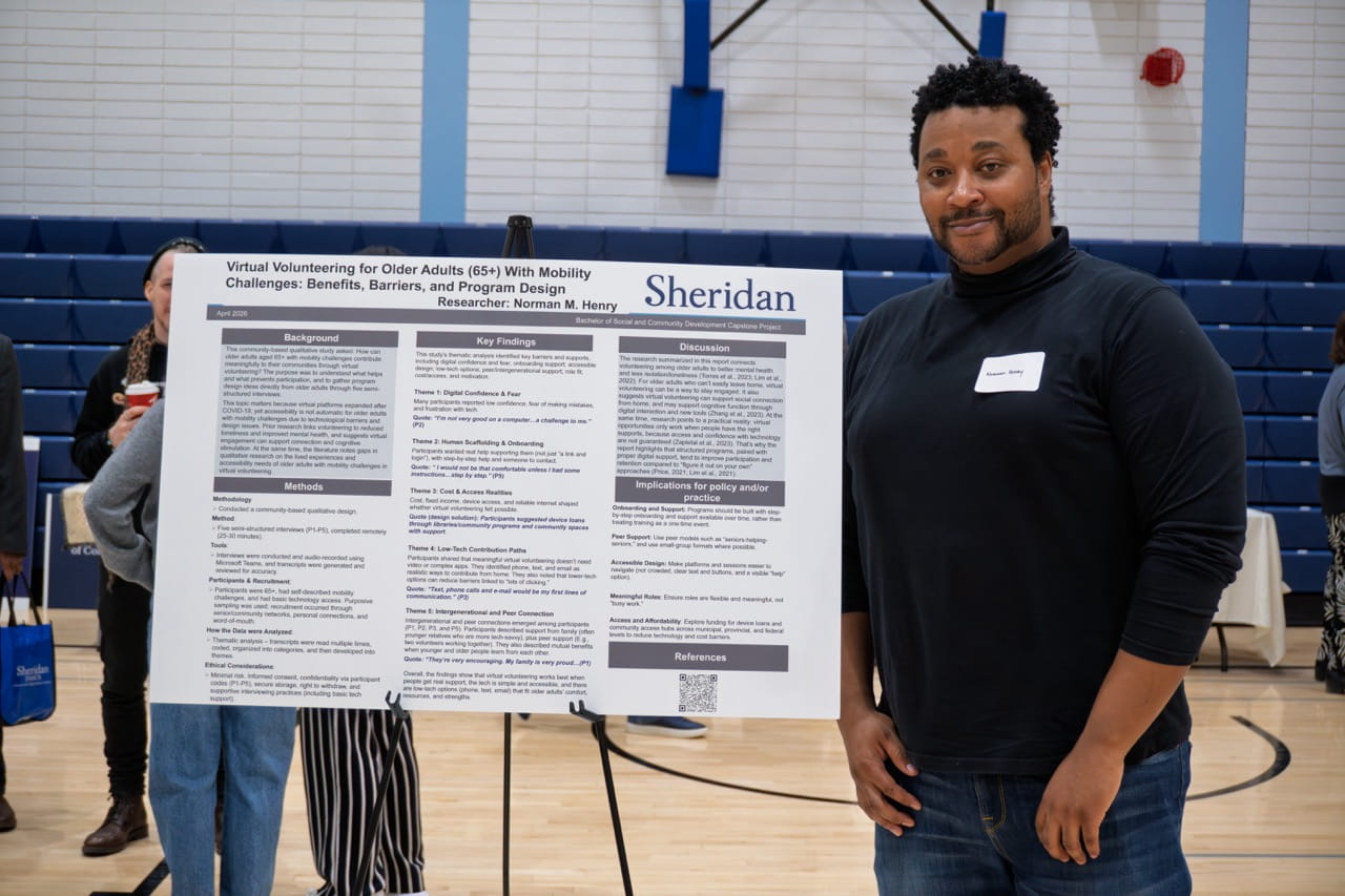 Student Norman Henry stands next to a large printout displaying his research findings