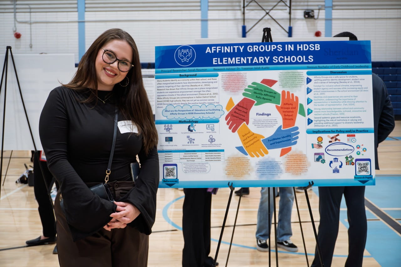 Sheridan student Sarah Newman stands next to a large printout displaying her research findings