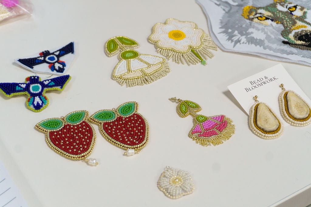 An arrangement of beaded artwork on a table, including a thunderbird and strawberries