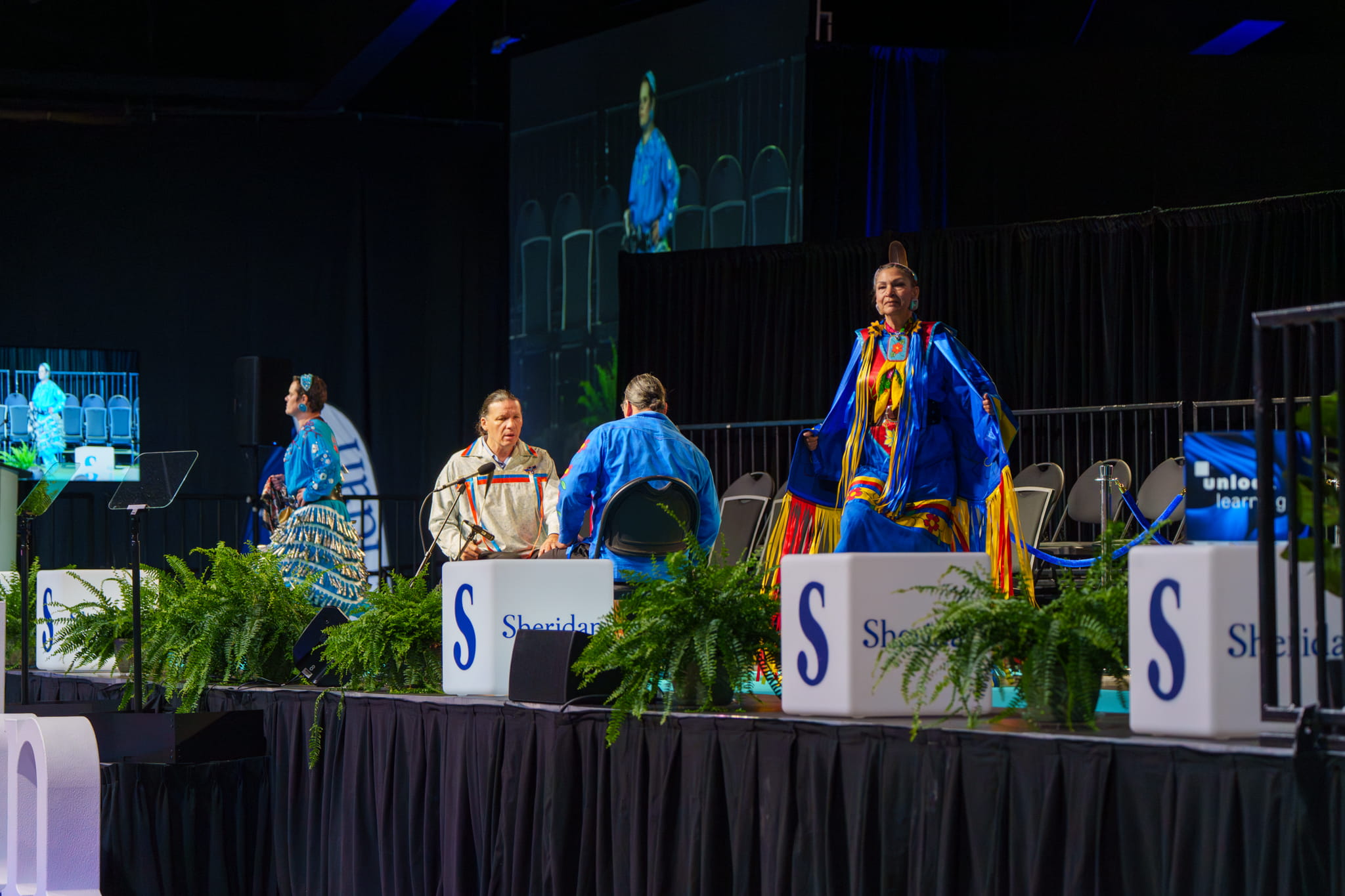 The Spirit Vision Singers and Dancers and drummers perform opening songs on the stage at convocation.