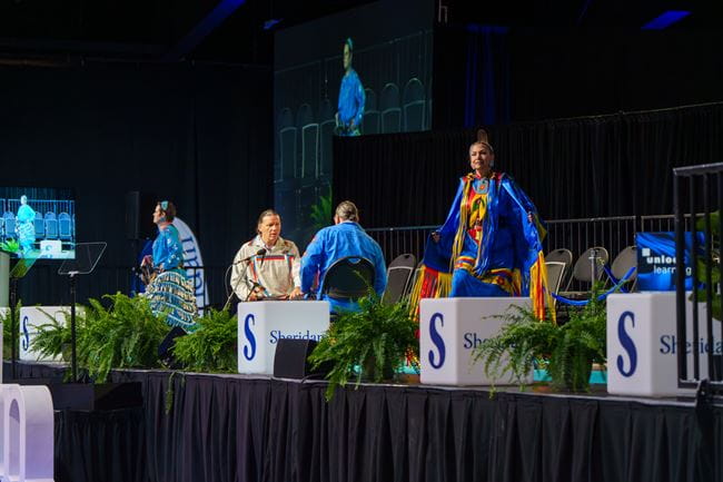The Spirit Vision Singers and Dancers and drummers perform opening songs on the stage at convocation.