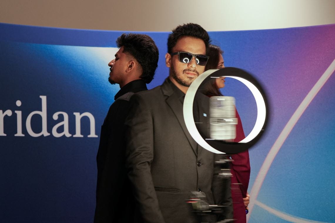 Three students, one wearing sunglasses, stand back to back at the 3D camera.