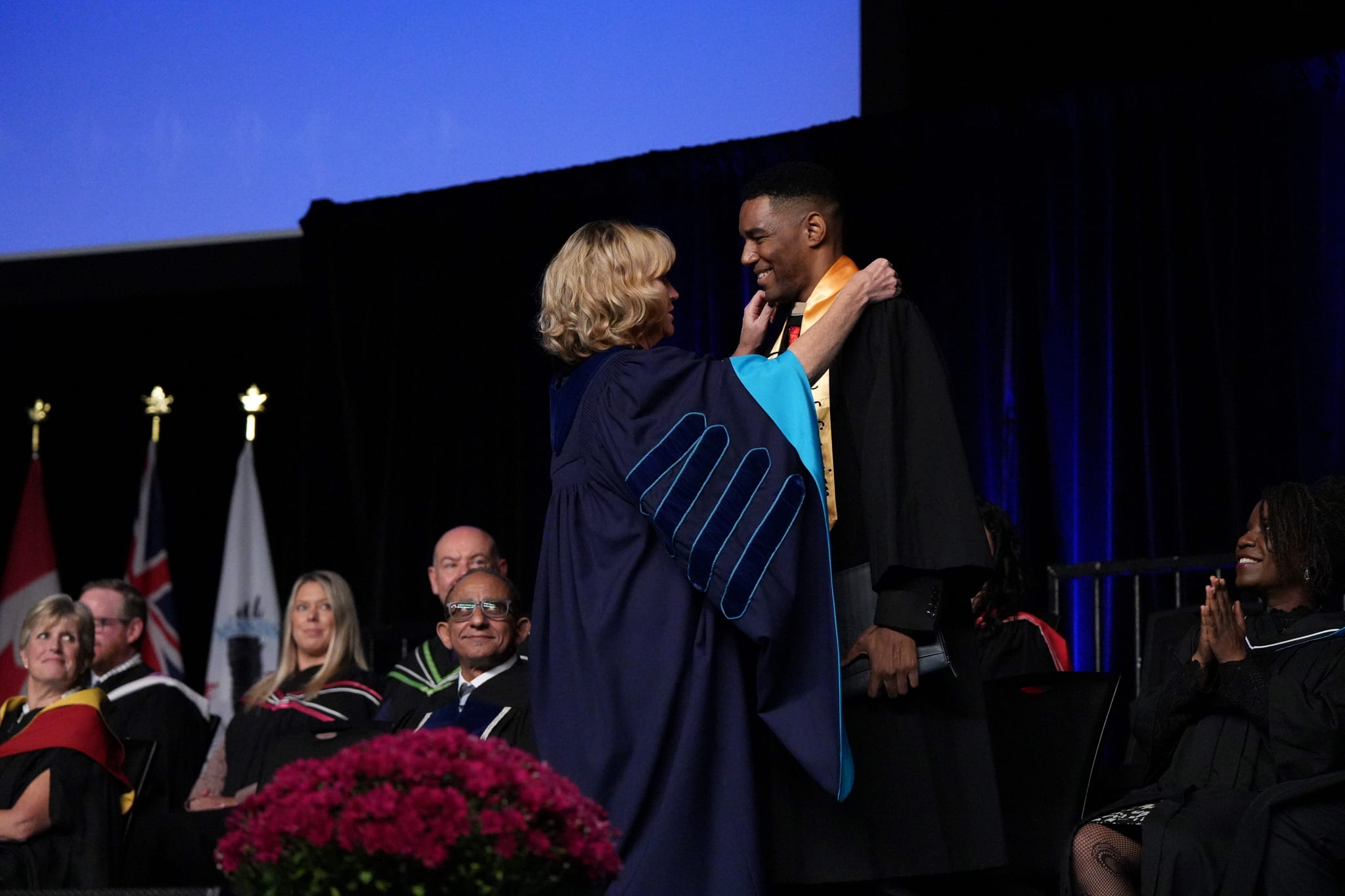President Janet Morrison adjusts the stole of valedictorian Jason-Tyler Edwards on stage before his speech.