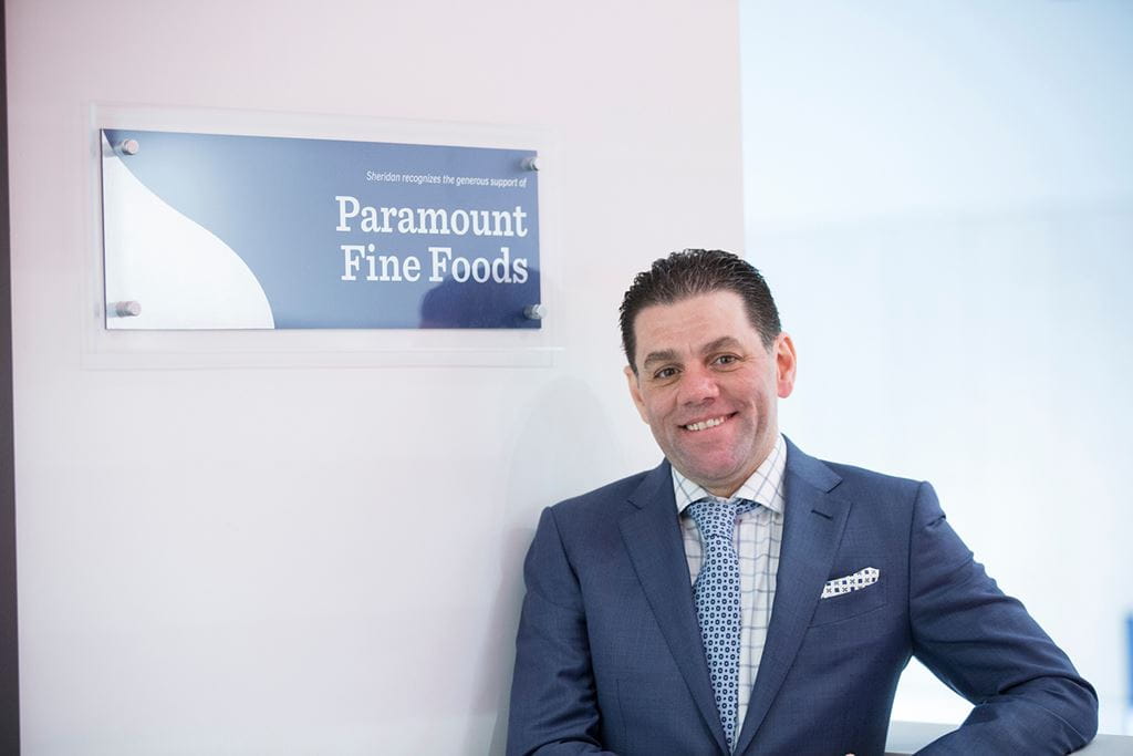 Mohamad Fakih standing in front of a Paramount Fine Foods donor sign