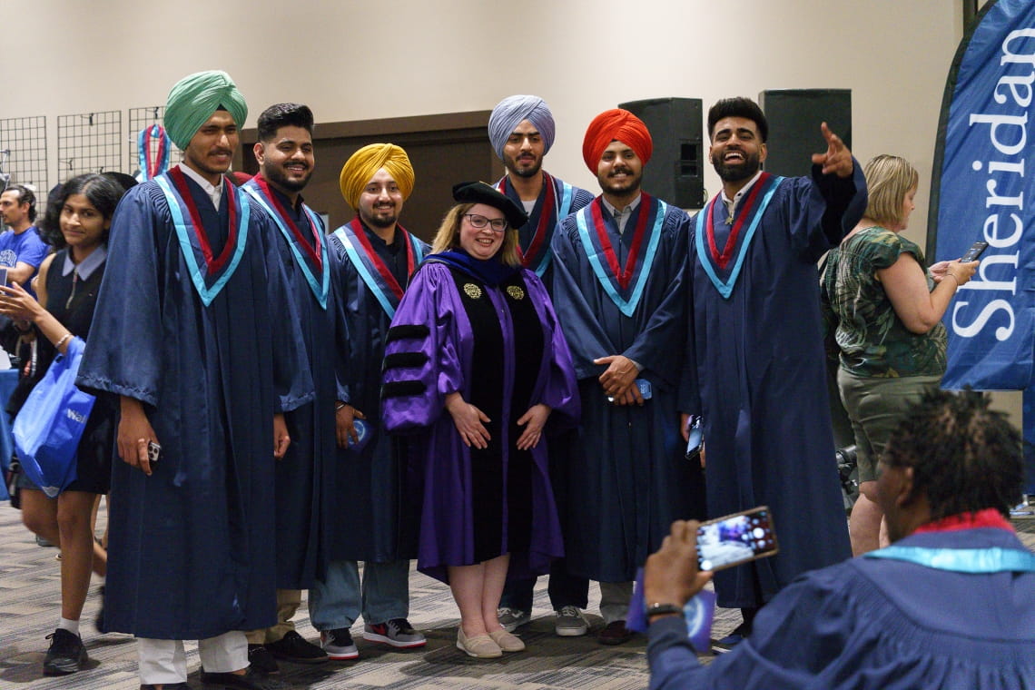 Grads from the Faculty of Applied Science and Technology pose with their Dean while their photo is taken.