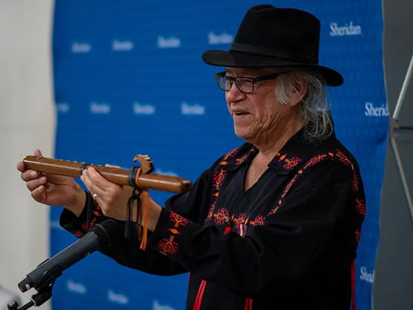 Rene Meshake holding up a pipigwan flute