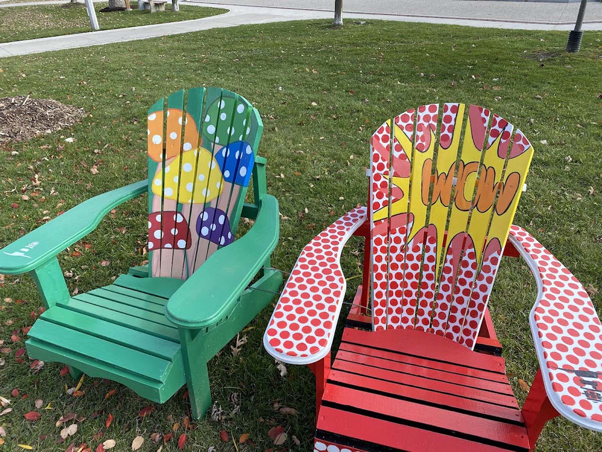 Two colourful Muskoka chairs designed and painted by Sheridan students on display in Bronte Heritage Waterfront Park.