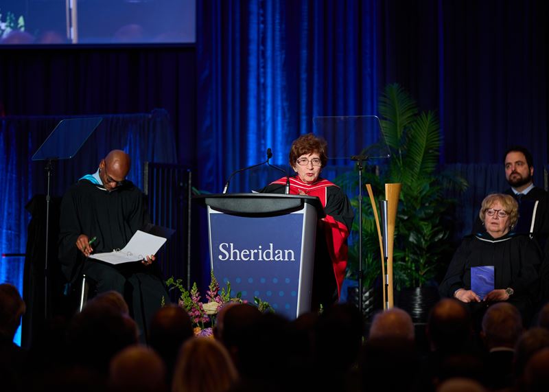Dr. Katherine Janzen stands at a podium to deliver her remarks.