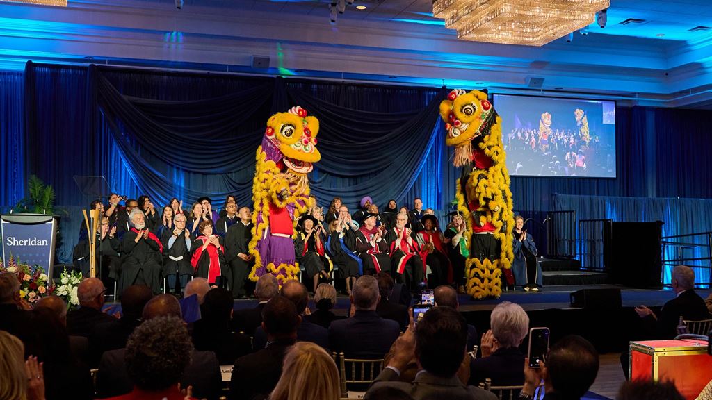 The lion dance takes place on stage with the platform party with the audience looking on.