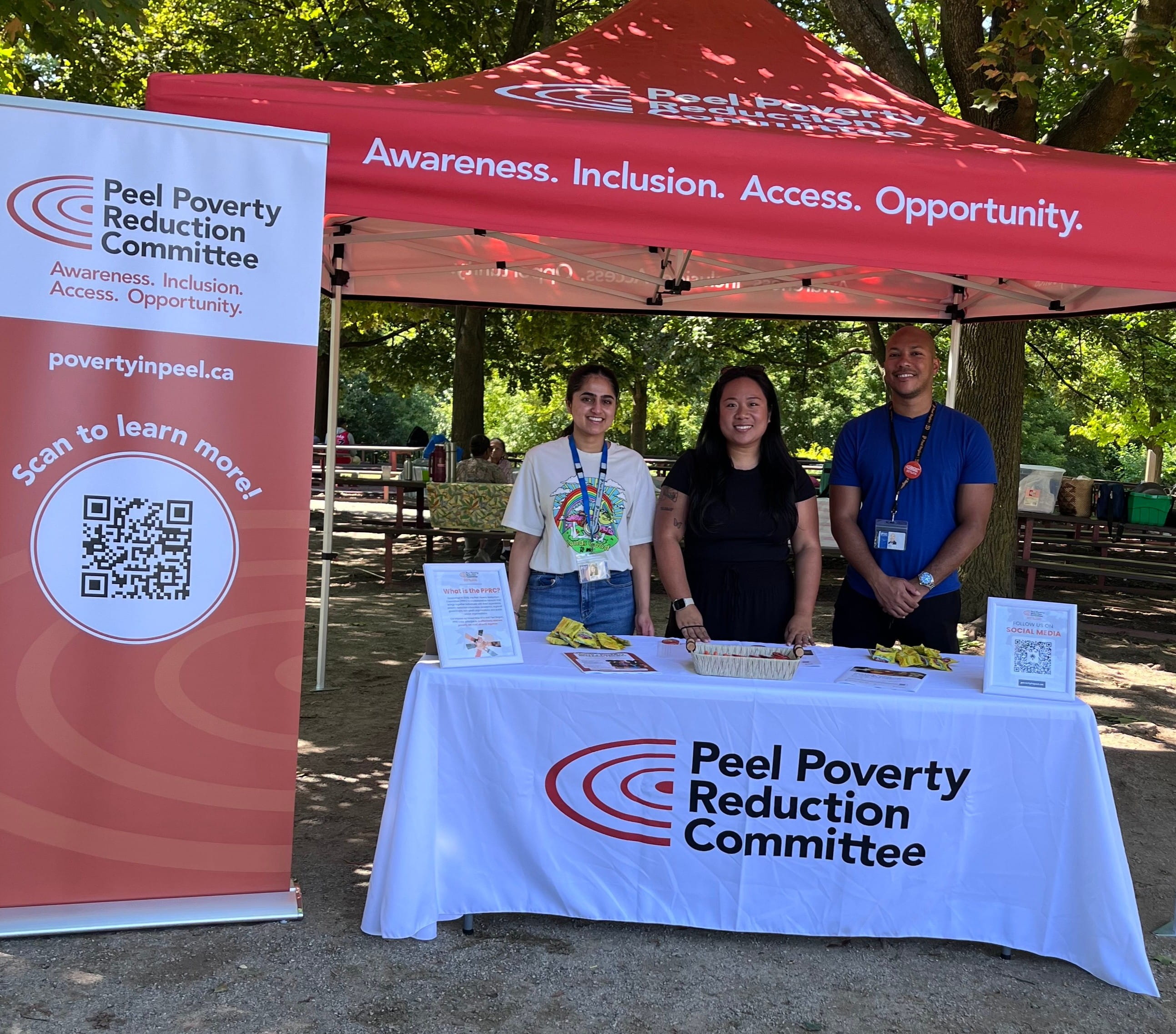 Valedictorian Jaspreet Kaur stands at a table with two people where they are promoting the Peel Poverty Reduction Committee.