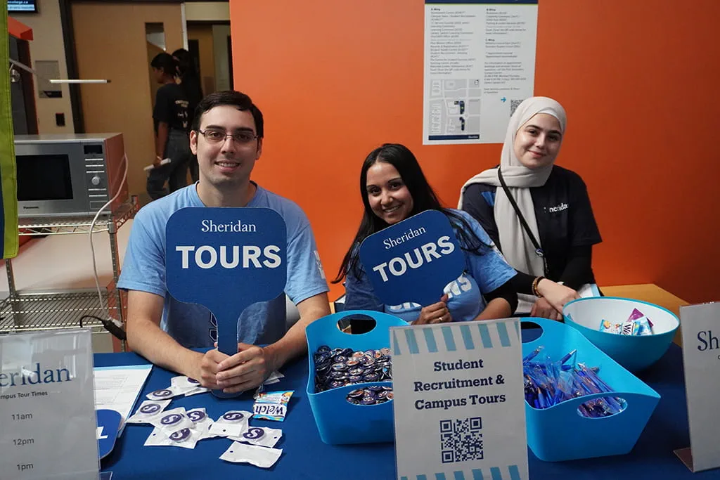 Members of Sheridan's student recruitment team and student ambassadors holding campus tour signs