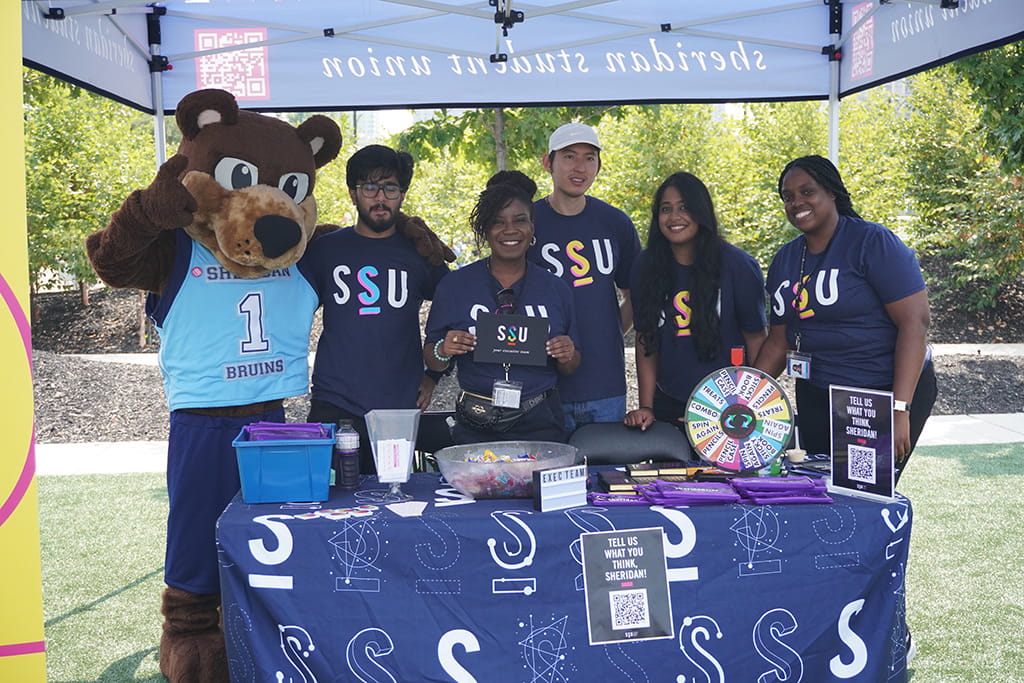 Sheridan Student Union (SSU) President, Ganyo Soh poses for a photo with team members and Sheridan's mascot, Bruno 