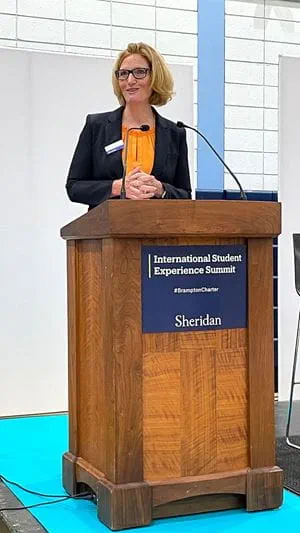 Janet Morrison standing behind a podium that reads 'International Student Experience Summit'