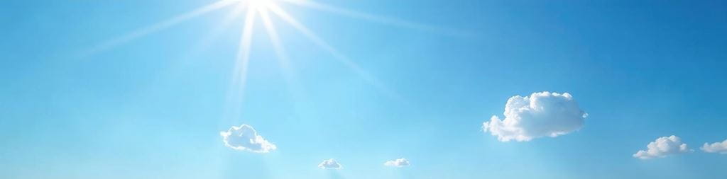 The sun shines atop a blue sky, surrounded by a few small clouds