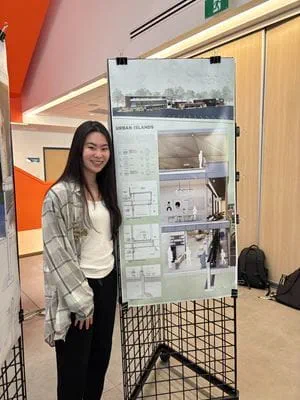 Valedictorian Aika Tsoi stands beside a project display.