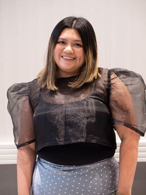 Valedictorian Geneva Garcia smiles, wearing a black blouse and blue skirt.
