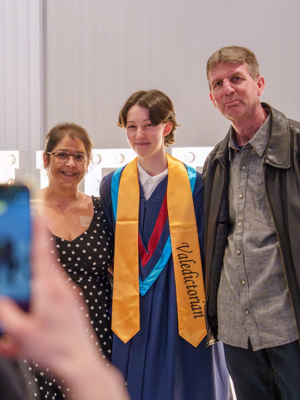 Valedictorian Mackenzie McPhee stands with her parents.