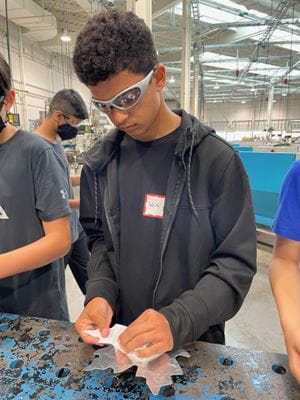 14-year-old Will Holmes-Ramroop cleans a metal maple leaf that was stamped in Sheridan's Magna Skilled Trades Centre