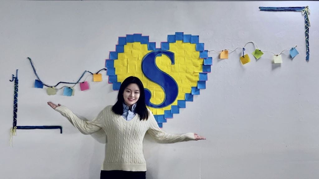 Zhilin Guo stands in front of her interactive art installation Making Connections: From Home to Sheridan
