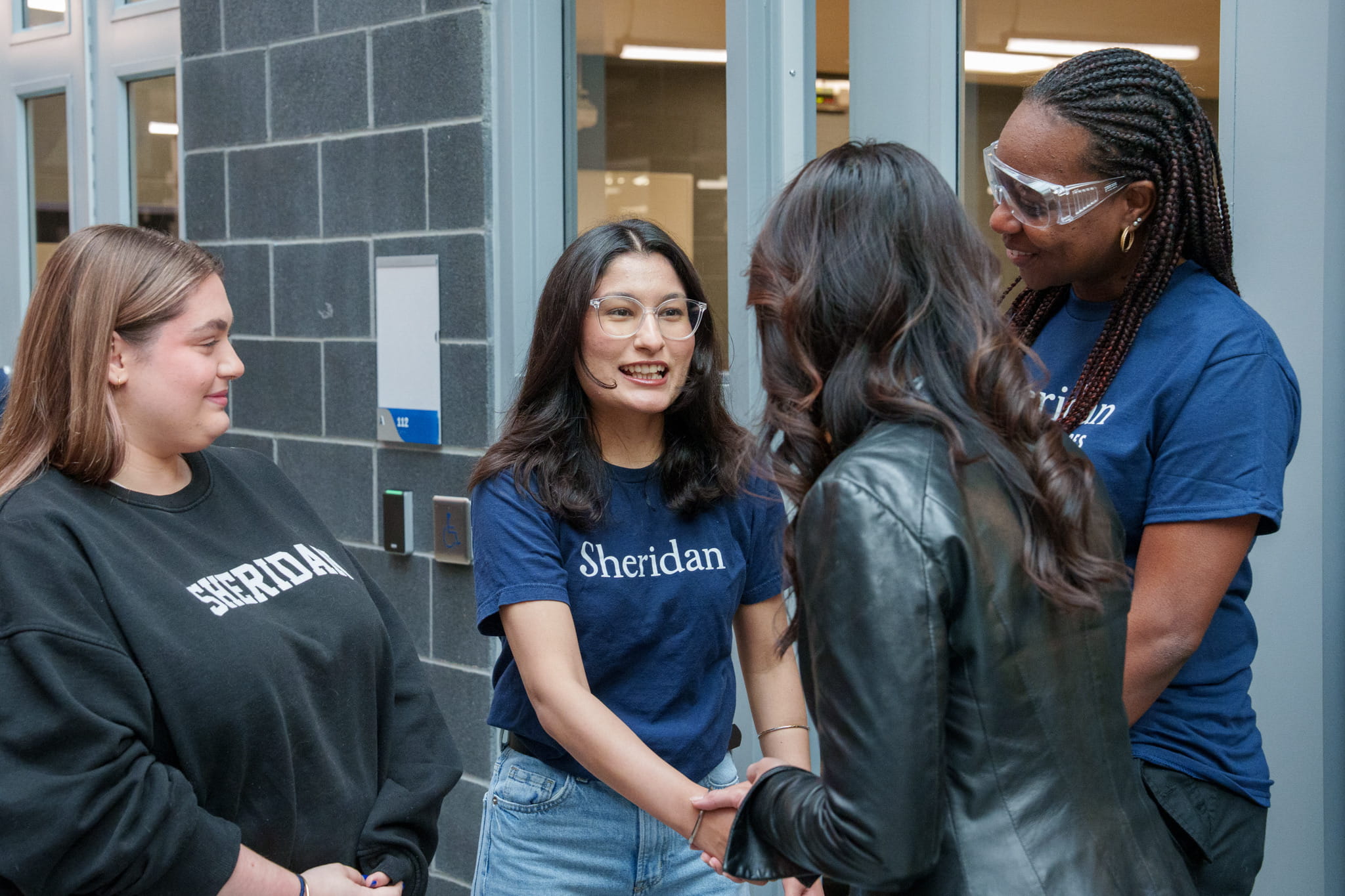 A Sheridan student smiles while shaking hands with federal Minister Rechie Valdez