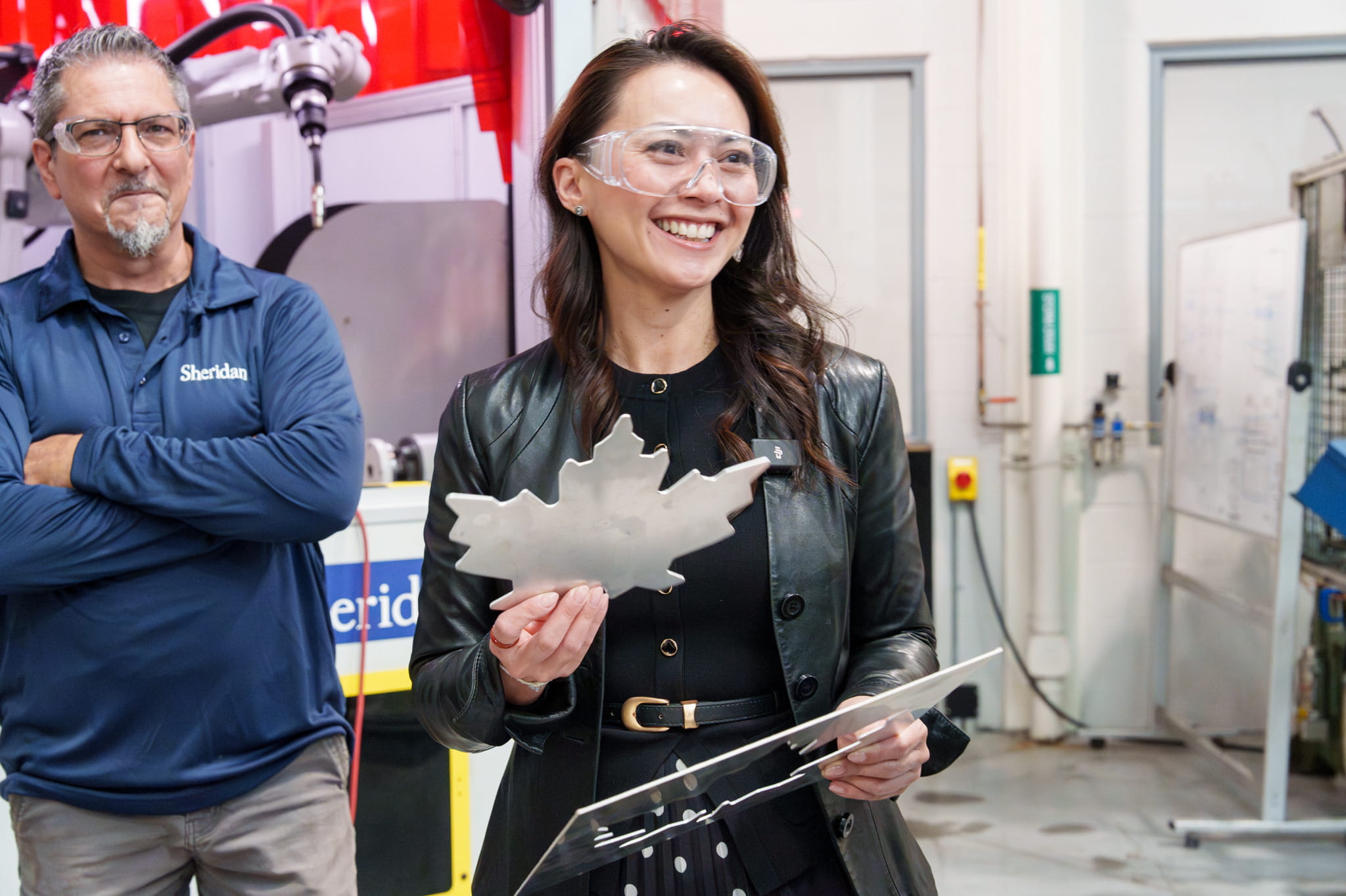 Federal Minister Rechie Valdez smiles as she holds a metal maple leaf created by Sheridan's die cutting machine