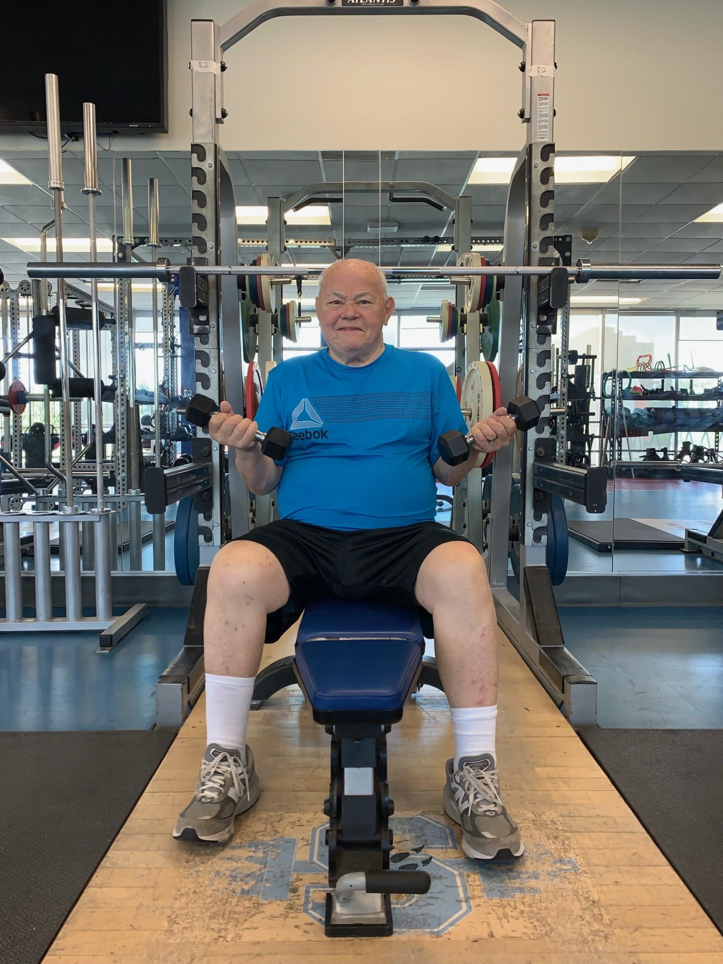 Helmut Knobl is pictured seated on an exercise machine with weights in both hands