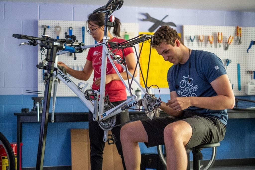 Two people working on bicycle repairs at the Sheridan Bike Hub