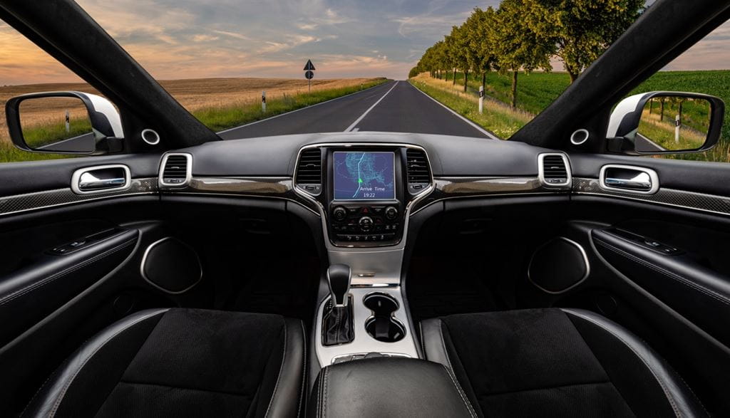 A view of the dashboard of a vehicle as it drives down a country road